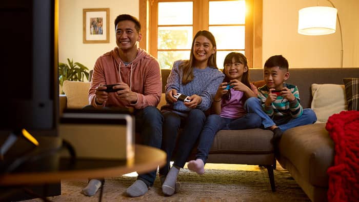 A family is shown playing on a sofa.