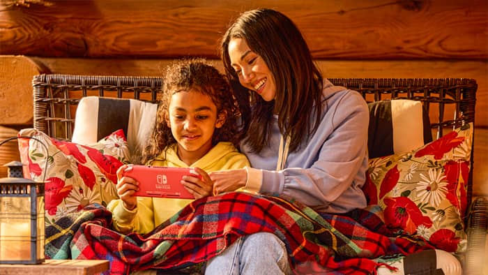 A woman and young girl are playing on a Nintendo Switch Lite system.