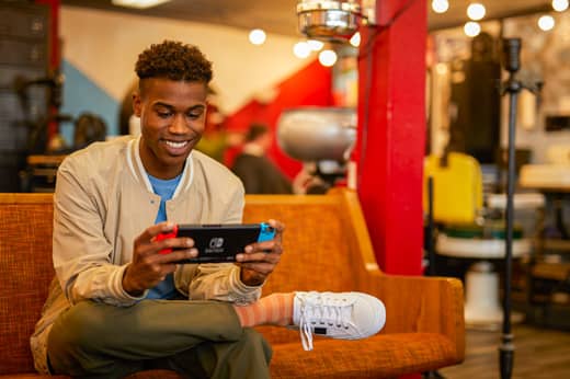 A man is smiling while playing a game of Big Brain Academy: Brain vs. Brain on his Nintendo Switch system.